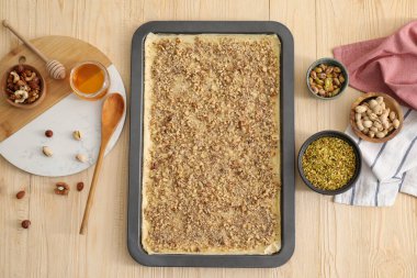 Lezzetli baklava yapıyorum. Hamur ve malzemelerle pişirme tavası ahşap masada, düz yerde.