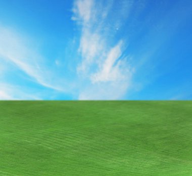 Parlak mavi gökyüzünün altında yeşil çimenli güzel çimenler ve bulutlar.