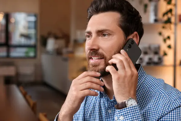 Kafede telefonla konuşan yakışıklı bir adam.