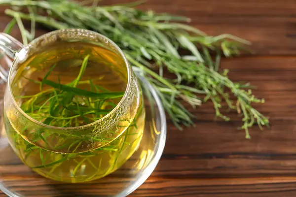 stock image Cup of homemade tarragon tea on wooden table, closeup. Space for text