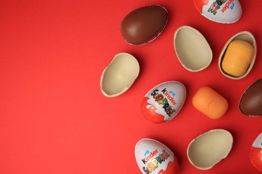 Sveti Vlas, Bulgaristan - 29 Haziran 2023: Kırmızı zemin üzerinde Kinder Surprise Eggs ve plastik kapsüller, düz zemin. Metin için boşluk