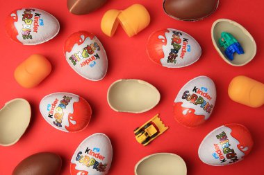Sveti Vlas, Bulgaristan - 29 Haziran 2023: Kinder Sürpriz Yumurtaları, plastik kapsüller ve kırmızı arka planda oyuncaklar, düz zemin