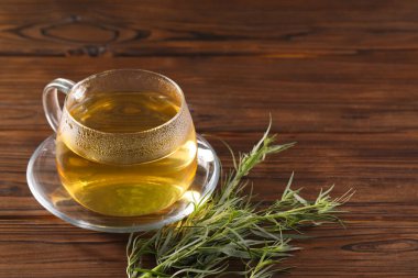 Bir fincan ev yapımı bitki çayı ve ahşap masada taze tarhun yaprağı. Metin için boşluk