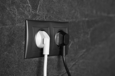 Koyu gri duvarda prizleri olan prizler, yakın plan. Elektrik arzı