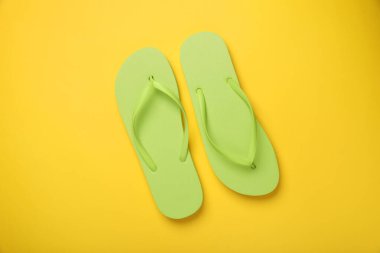 Sarı arka planda şık yeşil parmak arası terlikler, üst görünüm