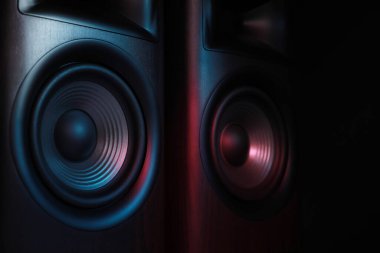 Modern sound speakers in neon light on black background, closeup clipart