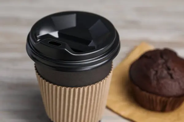 Paper cup with black lid on table, closeup. Coffee to go