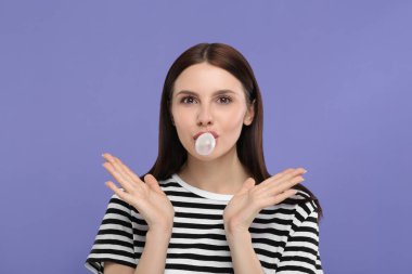 Açık mor arkaplanda sakız üfleyen güzel kadın, metin için boşluk