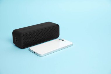 Portatif bluetooth hoparlör ve açık mavi arka planda akıllı telefon, mesaj için boşluk. Ses ekipmanları