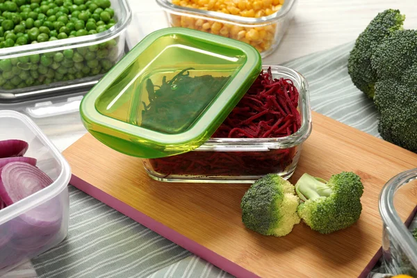 Containers with cut beetroot and fresh products on table. Food storage