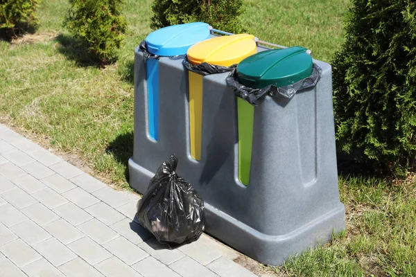 Plastic bag with garbage and recycling bins outdoors. Waste sorting