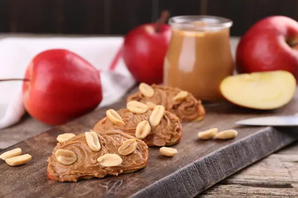 Pieces of fresh apple with peanut butter on wooden table