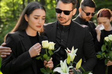 Dışarıda çiçekli üzgün insanlar yas tutuyor. Cenaze töreni.