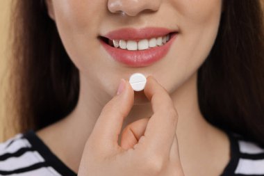 Bej arka planda hap alan kadın, yakın plan.