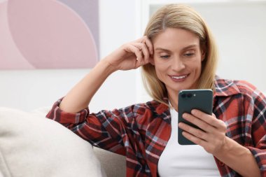 Mutlu kadın evde akıllı telefonla mesaj gönderiyor.