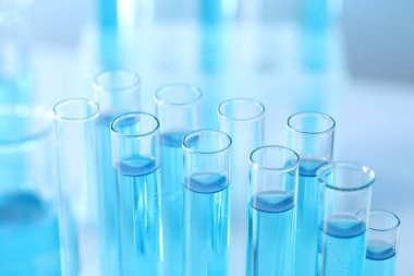 Laboratuvarda açık mavi sıvıyla test tüpleri, yakın plan.