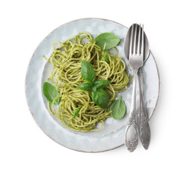 Beyaz arka planda pesto soslu lezzetli makarna fesleğen ve çatal bıçak seti.