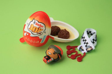 Sveti Vlas, Bulgaristan - 29 Haziran 2023: Tatlı şekerli Kinder Yumurtası ve açık yeşil arka planda oyuncaklar