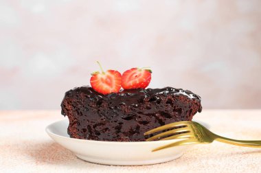 Bej desenli masasında çilekli çikolatalı kek.