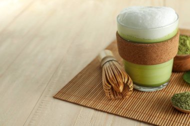 Cam bardak taze kibrit latte, pudra ve bambu çırpısı ahşap masada. Metin için boşluk