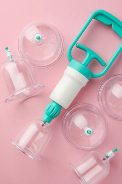 Pembe arka planda plastik bardaklar ve el pompamız var. Fincan terapisi.