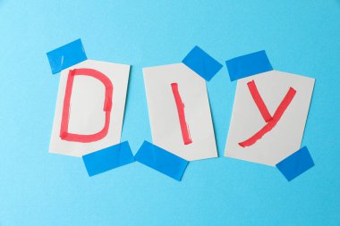 Açık mavi arkaplan için izolasyon bandıyla yapıştırılmış notlar üzerine yazılmış kısaltma DIY düz yatıyordu