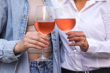 Kadehleri gül şarabıyla tokuşturan kadınlar.