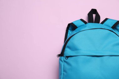 Mor arka planda açık mavi bir sırt çantası, üst manzara. Metin için boşluk