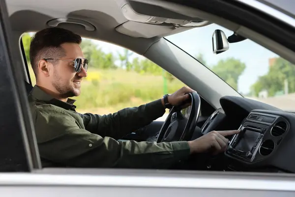 お気に入りのラジオを選択する 車のオーディオ上のボタンを押すサングラスを持つ男 — ストック写真