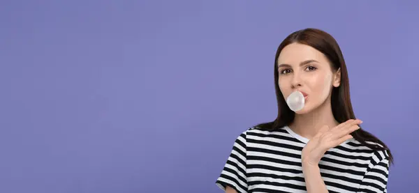 Beautiful woman blowing bubble gum on light purple background, space for text