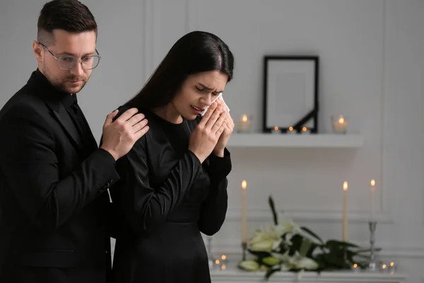 Sad couple mourning indoors, space for text. Funeral ceremony