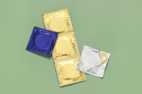Упакованные презервативы на светло-зеленом фоне, вид сверху. Safe sex
