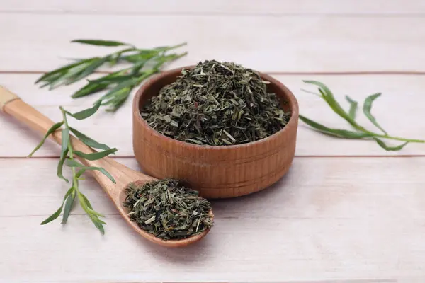 Dry and fresh tarragon on wooden table
