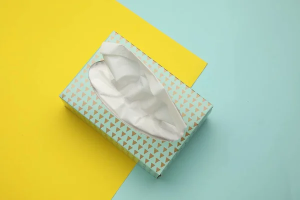 Box of paper tissues on color background, top view