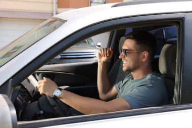 Araba sürerken radyo dinlemek. Şık güneş gözlüklü yakışıklı adam arabada müzikten zevk alıyor.