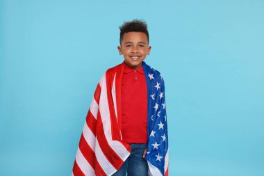 4 Temmuz - ABD 'nin Bağımsızlık Günü. Açık mavi arka planda Amerikan bayrağı taşıyan mutlu çocuk
