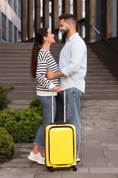 Long-distance relationship. Beautiful young couple with suitcase near building outdoors