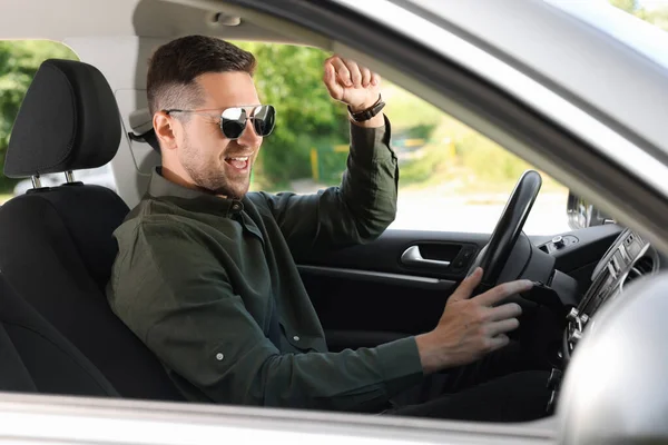お気に入りのラジオを選択する 車の中で音楽を楽しんでいるサングラスを持つ男 — ストック写真