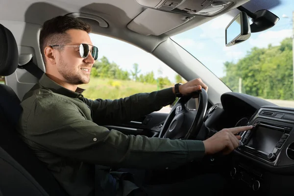 お気に入りのラジオを選択する 車のオーディオ上のボタンを押すサングラスを持つ男 — ストック写真
