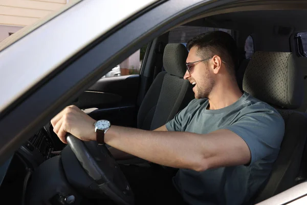 運転中にラジオを聴いている 車で音楽を楽しむスタイリッシュなサングラスを備えたハンサムな男 — ストック写真