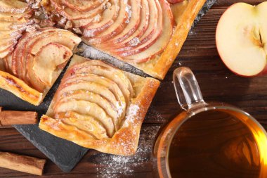 Tahta masada çay ile servis edilen taze pişmiş elmalı turta.