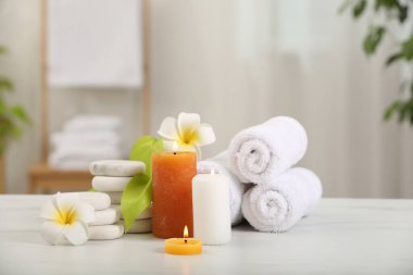 Beyaz mermer masa üzerinde farklı spa ürünleri ve plumeria çiçekleri içeren kompozisyon.