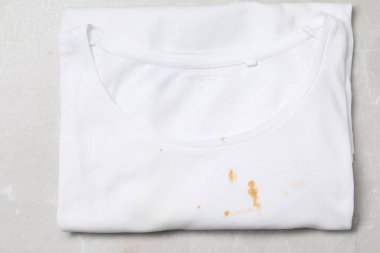 Açık gri mermer masa üzerinde sos lekeleri olan kirli tişört.