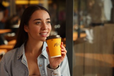 Lviv, Ukrayna - 26 Eylül 2023: Kafede seksi McDonald 's içkisi içen kadın, mesaj için yer