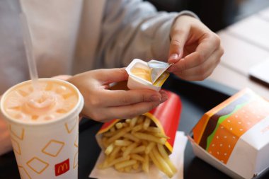 Lviv, Ukrayna - 26 Eylül 2023: Restorandaki masada McDonald 's sosunu açan kadın, yakın plan