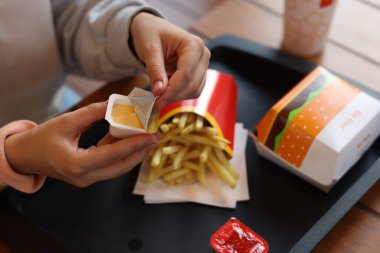 Lviv, Ukrayna - 26 Eylül 2023: Restorandaki ahşap masada McDonald 's sosunu açan kadın, yakın plan