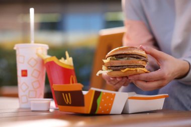 Lviv, Ukrayna - 26 Eylül 2023: Tahta masada McDonald 's menüsü olan kadın, yakın plan