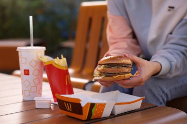 Lviv, Ukrayna - 26 Eylül 2023: Tahta masada McDonald 's menüsü olan kadın, yakın plan