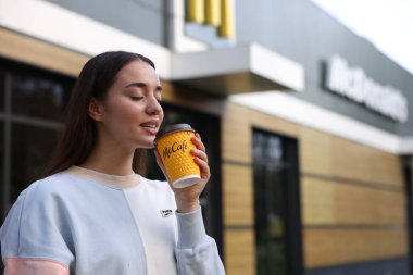 Lviv, Ukrayna - 26 Eylül 2023: Sıcak McDonald 's içen kadın açık havada, mesaj için yer