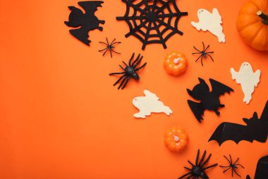 Turuncu arka planda yarasalar, balkabakları, hayaletler ve örümceklerle düz bir kompozisyon vardı. Cadılar Bayramı